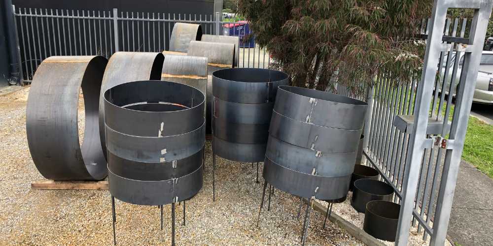 Large metal corten steel drums on concrete slab